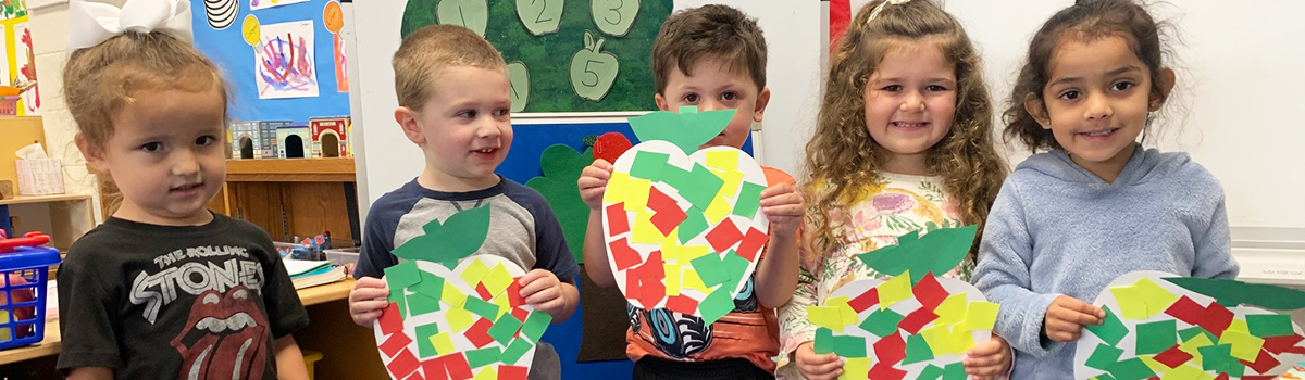 Young happy students holding up fall inspired artwork