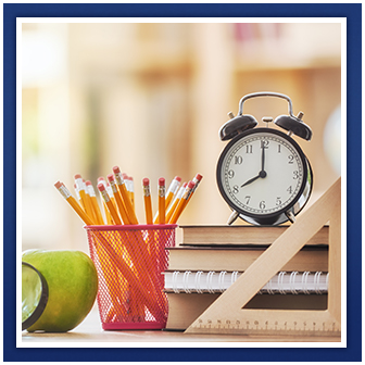 A clock, ruler, pencils, books, apple and magnifying glass