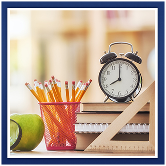 A clock, ruler, pencils, books, apple and magnifying glass
