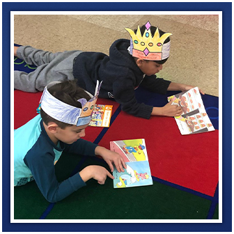 students reading on floor with paper crowns