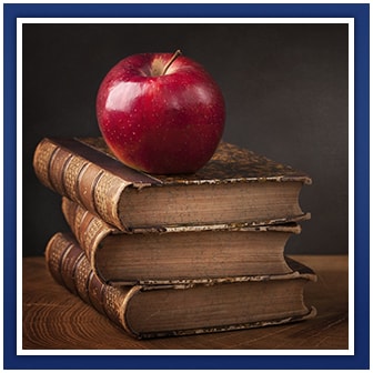 Apple sits on top of stacked books on a wooden surface