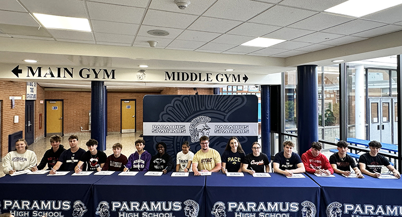 Paramus high school athletes proudly sitting at a long table after signing ceremony