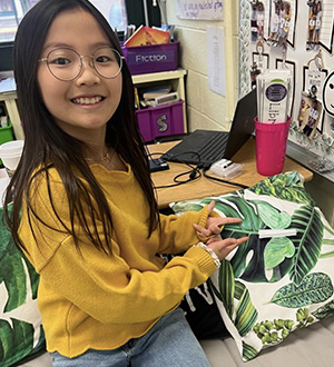 Student pointing at a paper butterfly on cloth