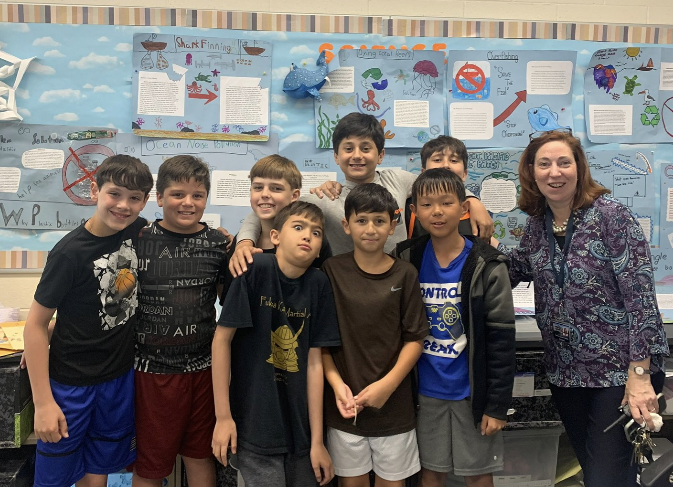 Adult standing next to students in a classroom