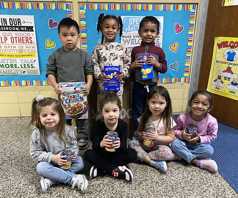 Early childhood students posing for a picture with their food drive donations