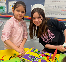 Two smiling students building leprechaun traps