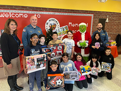 Memorial school students with toys they collected, police officers, and the Grinch