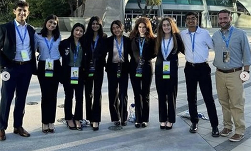 Eight students and instructor in front of building