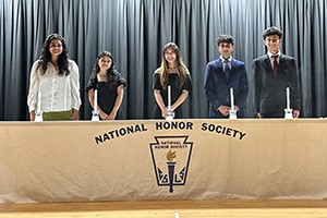 Five students standing behind a table that reads National Honor Society