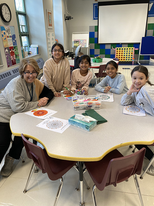 Teacher and students smiling from a round table in the classroom