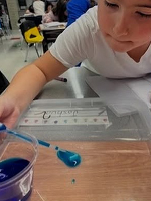 Student adding to a blue liquid