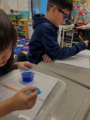 Student adding to a blue puddle