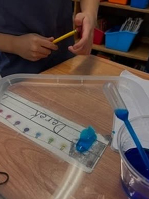 studentholding pencil next to blue liquid