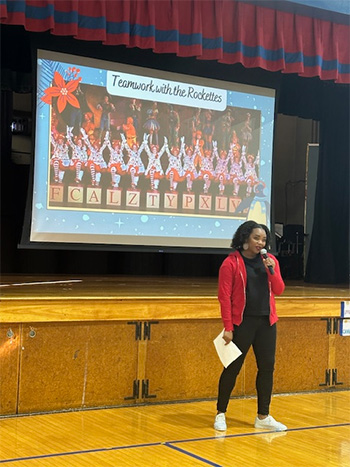 Member of the Rockettes during her presentation with large presentation screen behind her