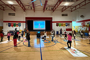 Students watching a screen show them how to do yoga