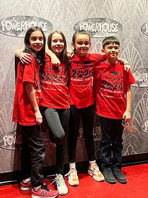 Four Memorial School fourth grade students posing in front of Powerhouse Studios wall