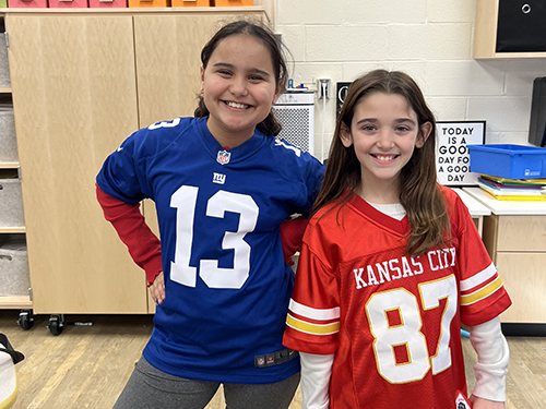Two girls smiling wearing 13 and 87 jerseys