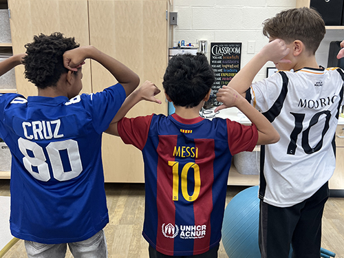 Three students showing back of numbered jerseys